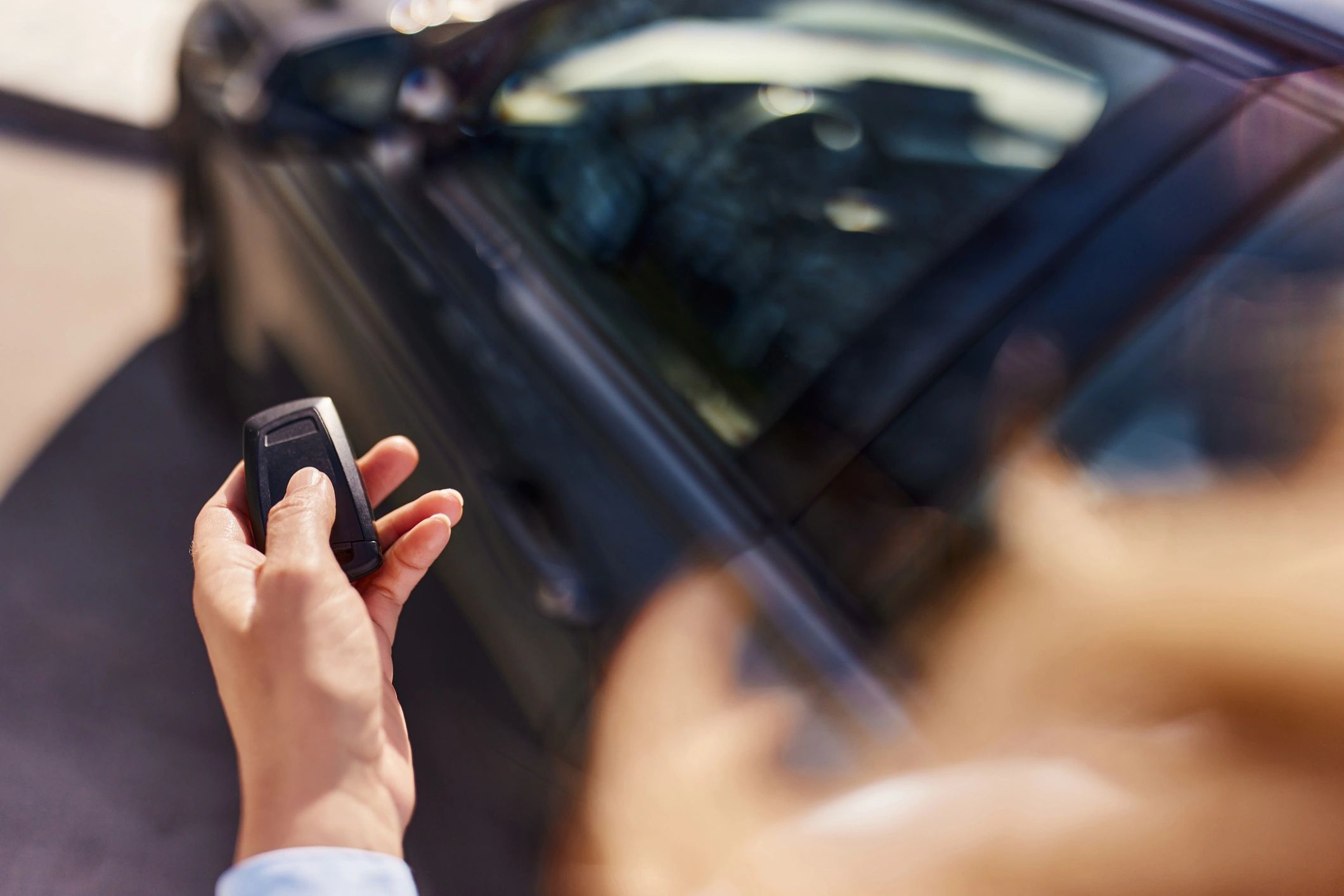 Person holding a car key near a vehicle door